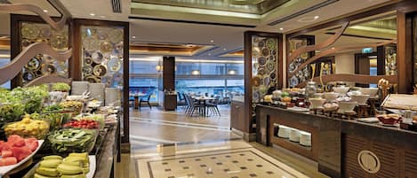 A buffet area with various food items and a dining area in the background.