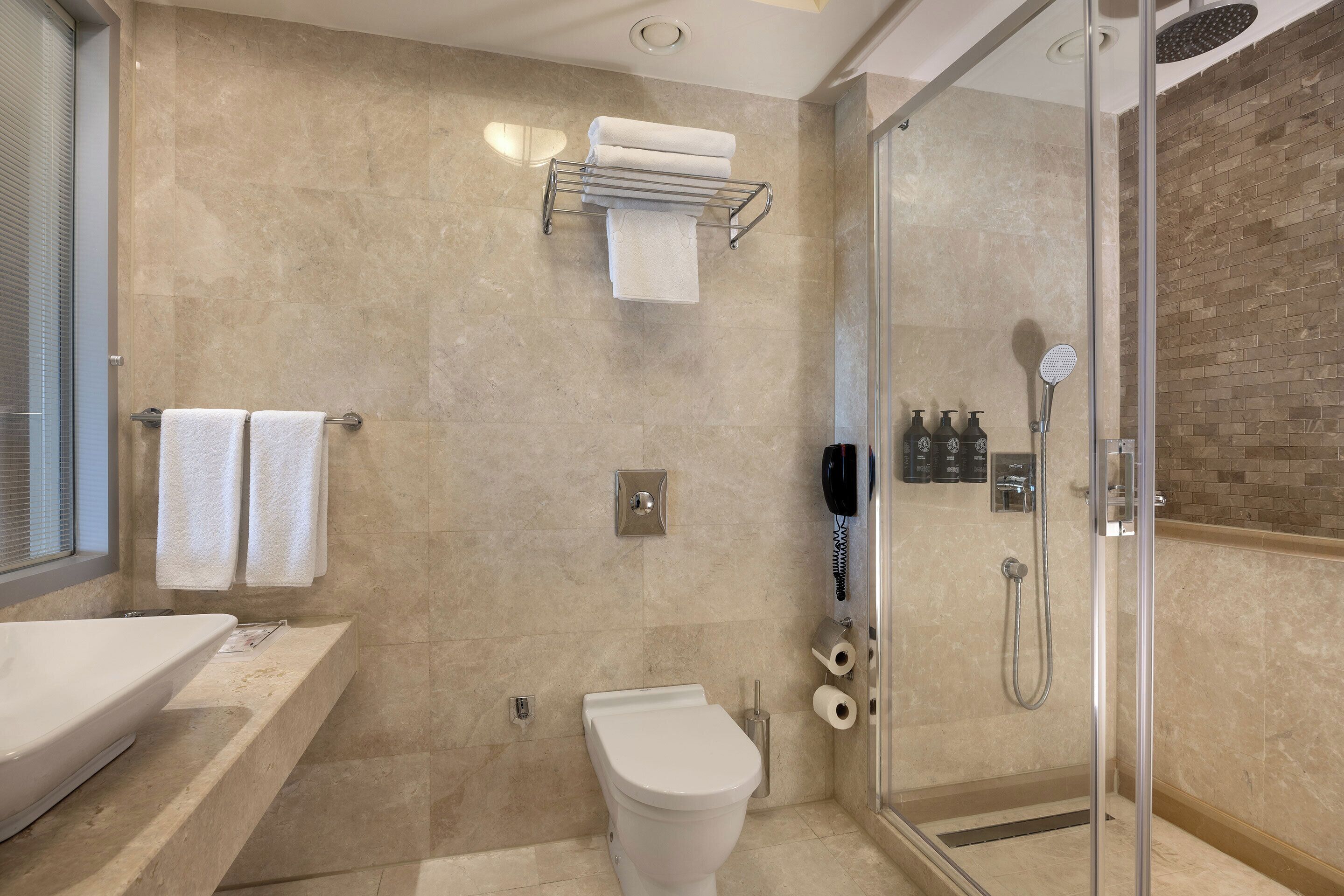 Een moderne badkamer met een douchecabine van glas, een wit toilet en een grote wastafel.