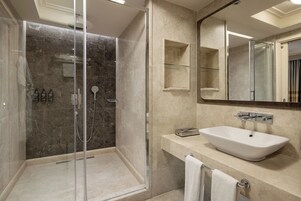 A modern bathroom with a glass-enclosed shower, a white sink, and a large mirror.