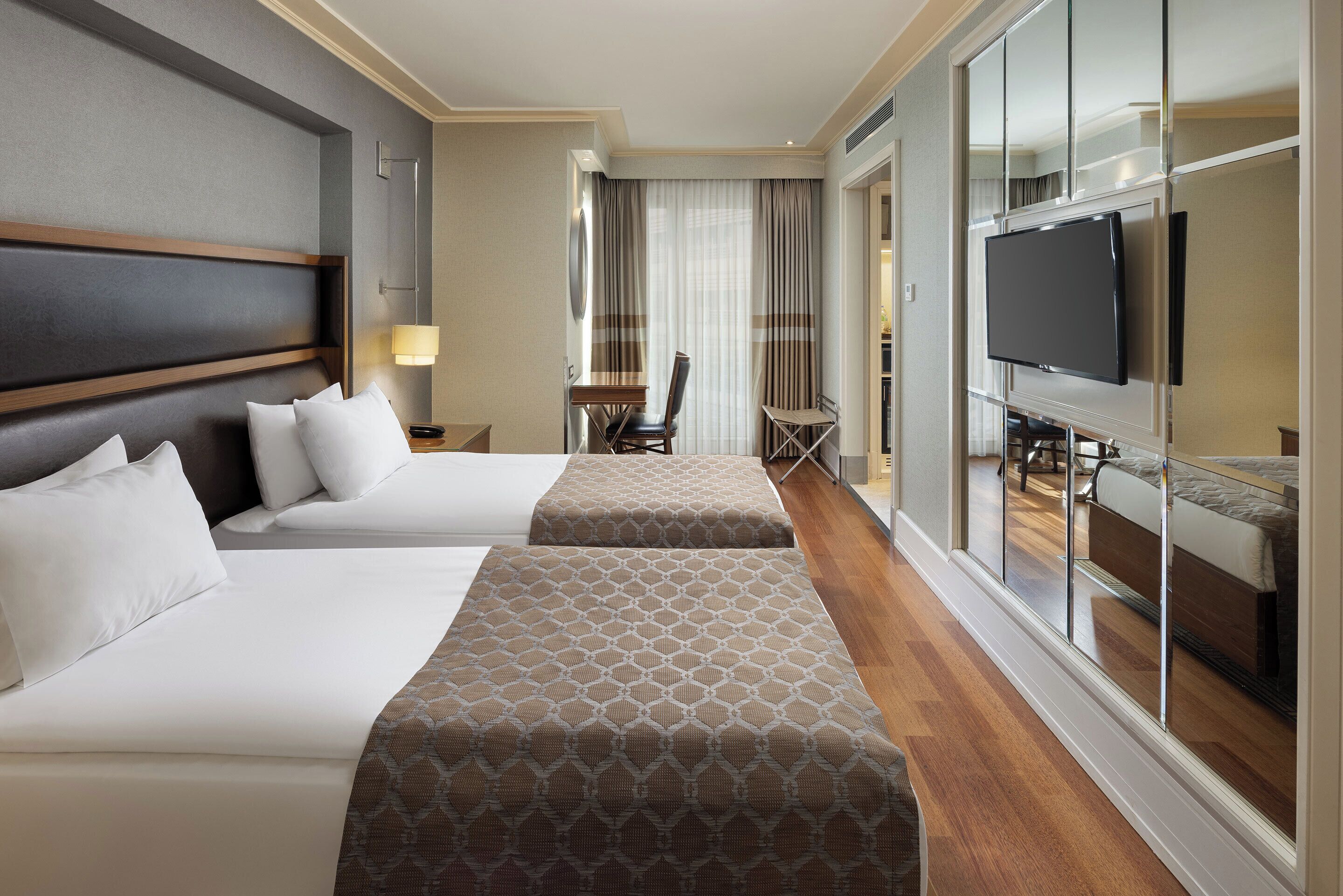 Habitación de hotel con dos camas, televisión, escritorio y silla.
