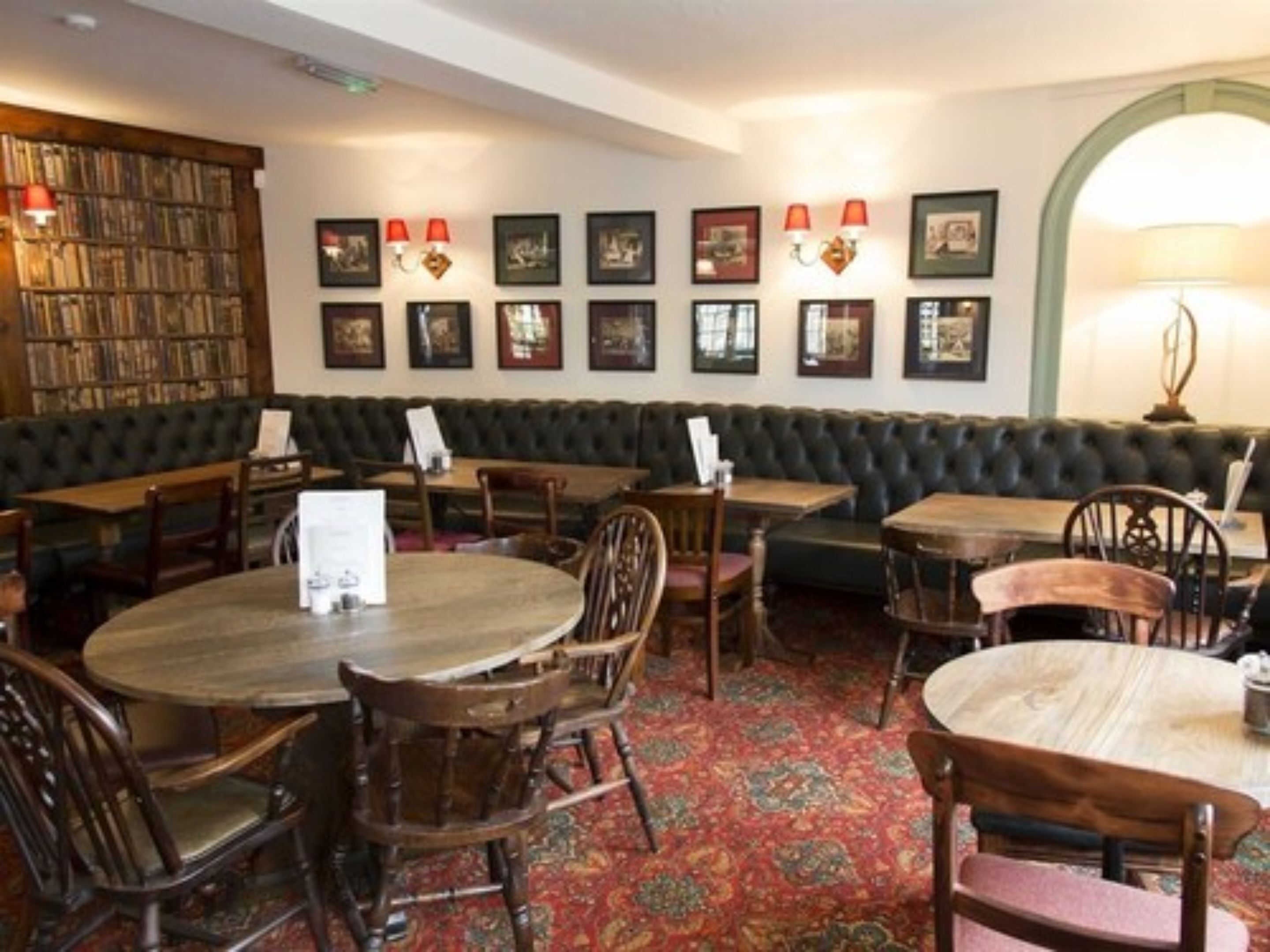 A cozy restaurant with a green cushioned bench seating area, wooden tables, and chairs.