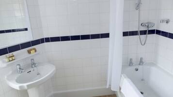Une salle de bain avec des carreaux blancs, un lavabo, une baignoire et une douche.