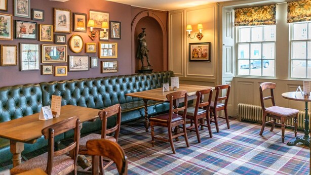 A cozy restaurant with a green upholstered bench, wooden tables, and chairs. - The Kings Arms Hotel - Inn (Melksham)
