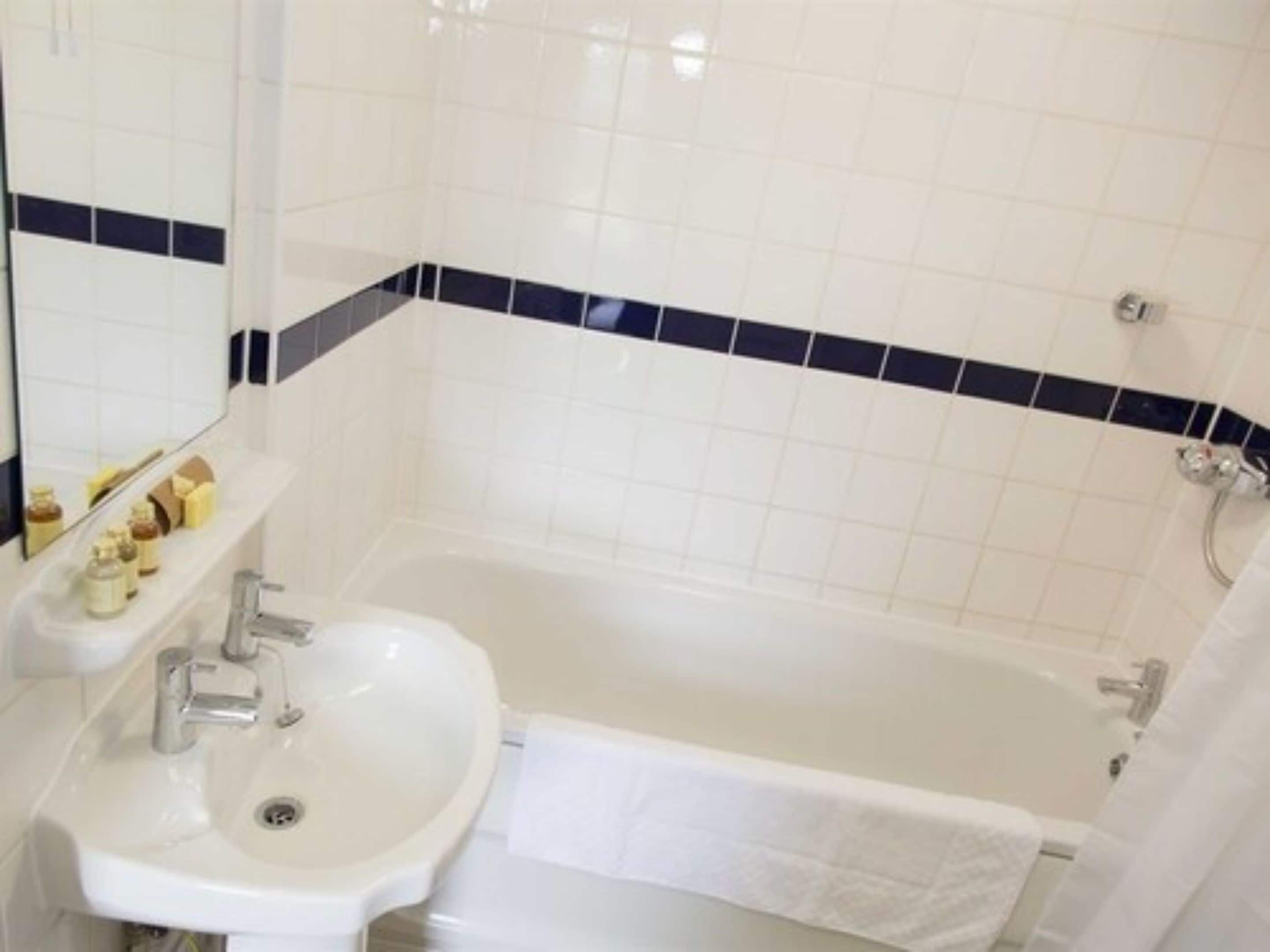 A bathroom with a white sink, mirror, and bathtub.