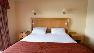 A hotel room with a large bed, two bedside tables, and a wooden headboard.