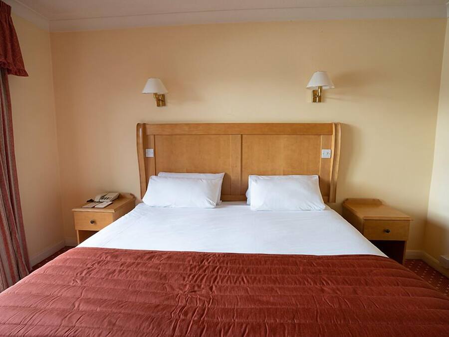A hotel room with a large bed, two bedside tables, and a wooden headboard.