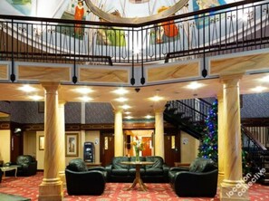 Eine Lobby mit einer imposanten Treppe, Ledersitzmöglichkeiten und einem Weihnachtsbaum.