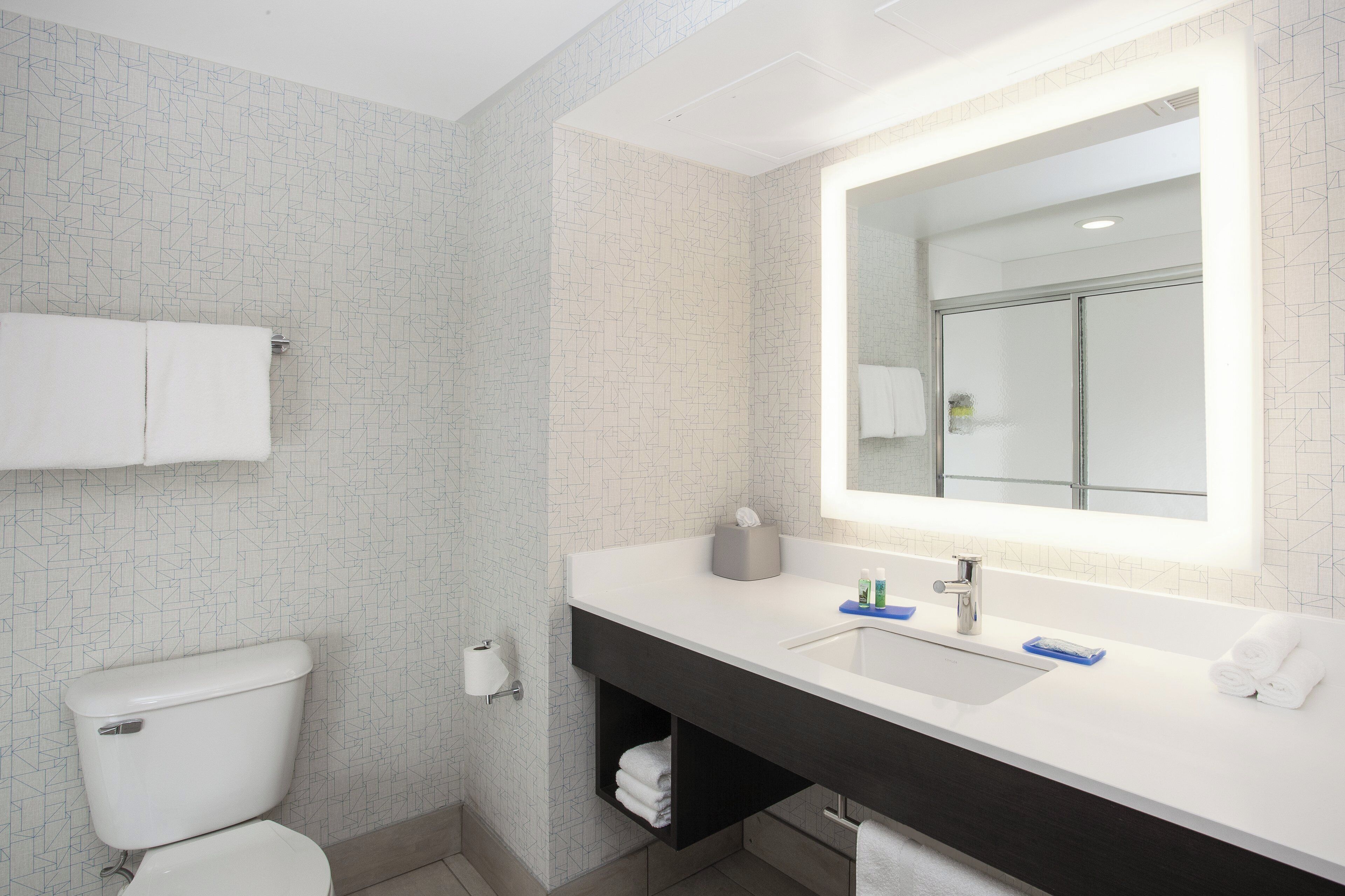 A modern bathroom with a toilet, sink, and mirror.