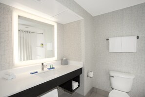 A modern bathroom with a white sink, black countertop, and a large mirror.