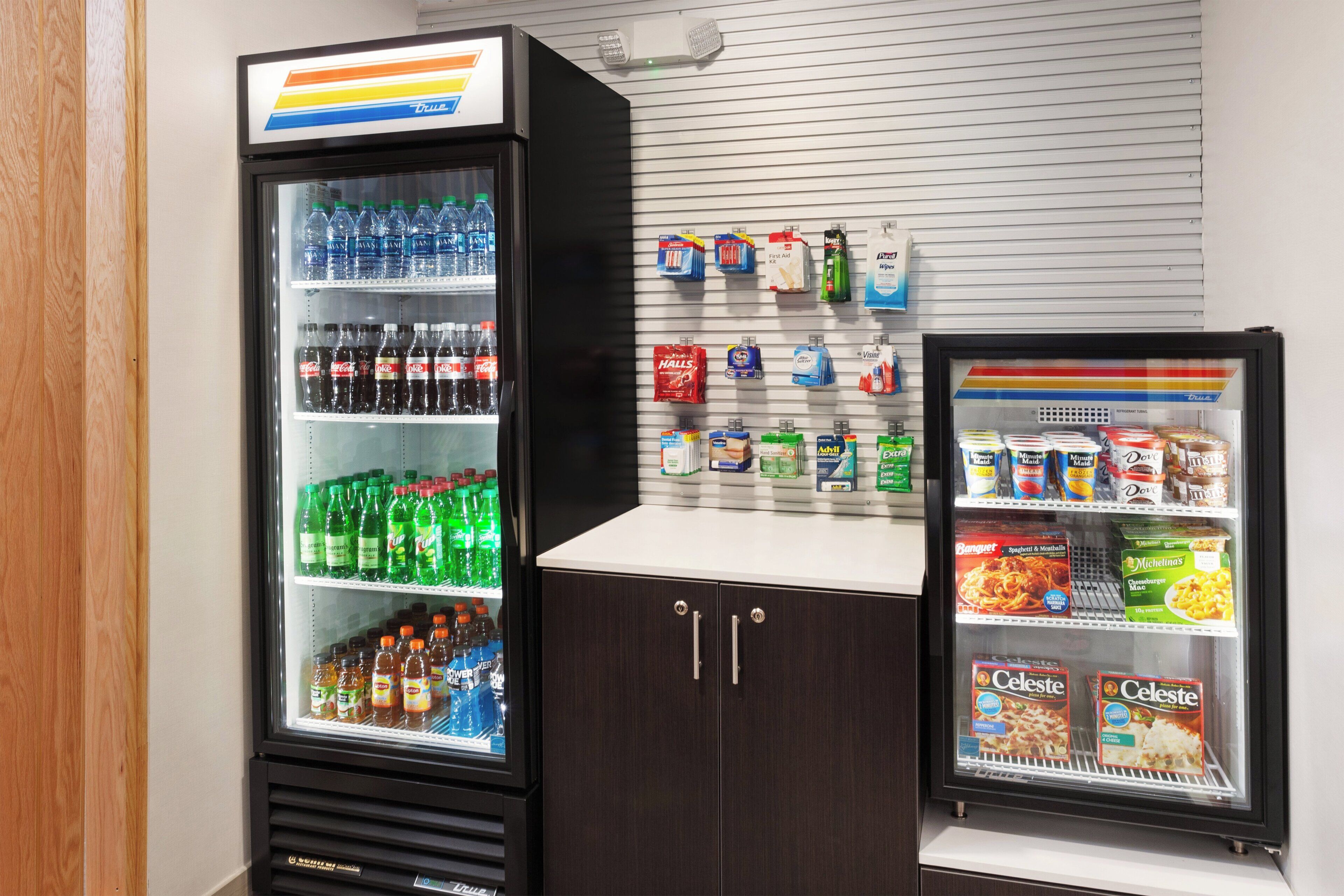 Een automaat met diverse dranken en snacks, een handdesinfecterend middel dispenser, en een koeltoog met bevroren producten.