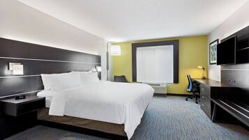 A hotel room with a bed, bedside tables, a desk, a chair, a TV, and a window.
