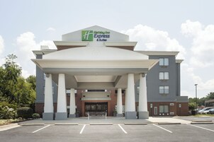 Edificio de Holiday Inn Express & Suites con un diseño moderno, que presenta una entrada destacada y un estacionamiento al frente.