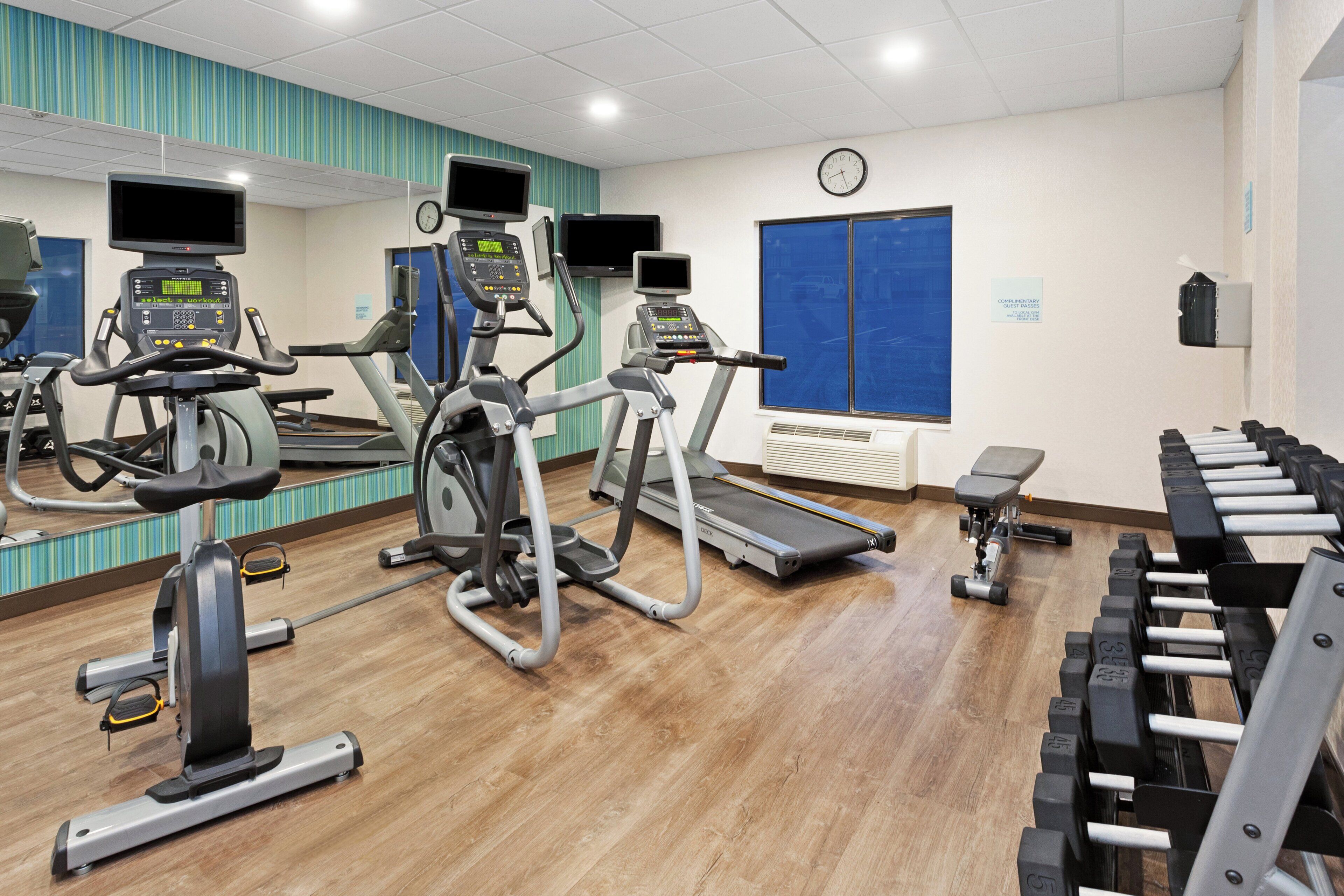 A gym with treadmills, elliptical machines, and a weight bench area.