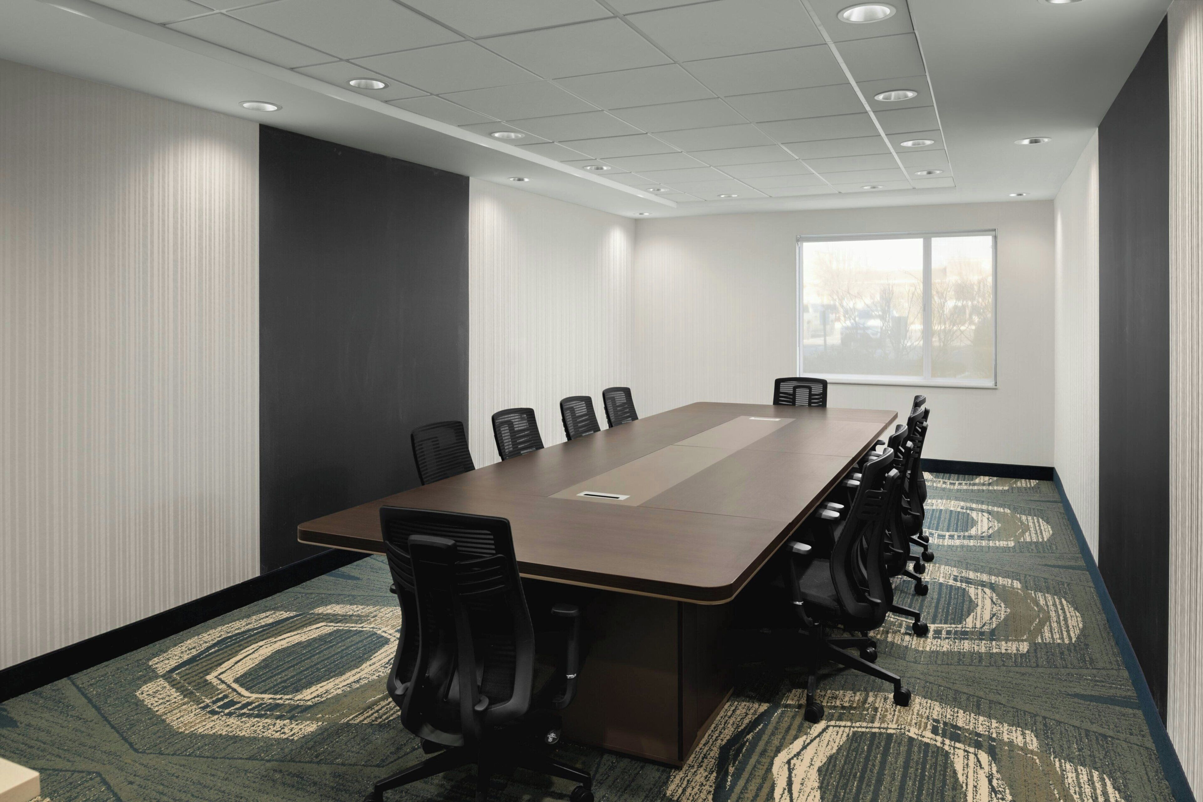 Une salle de conférence avec une longue table, des chaises et une fenêtre.