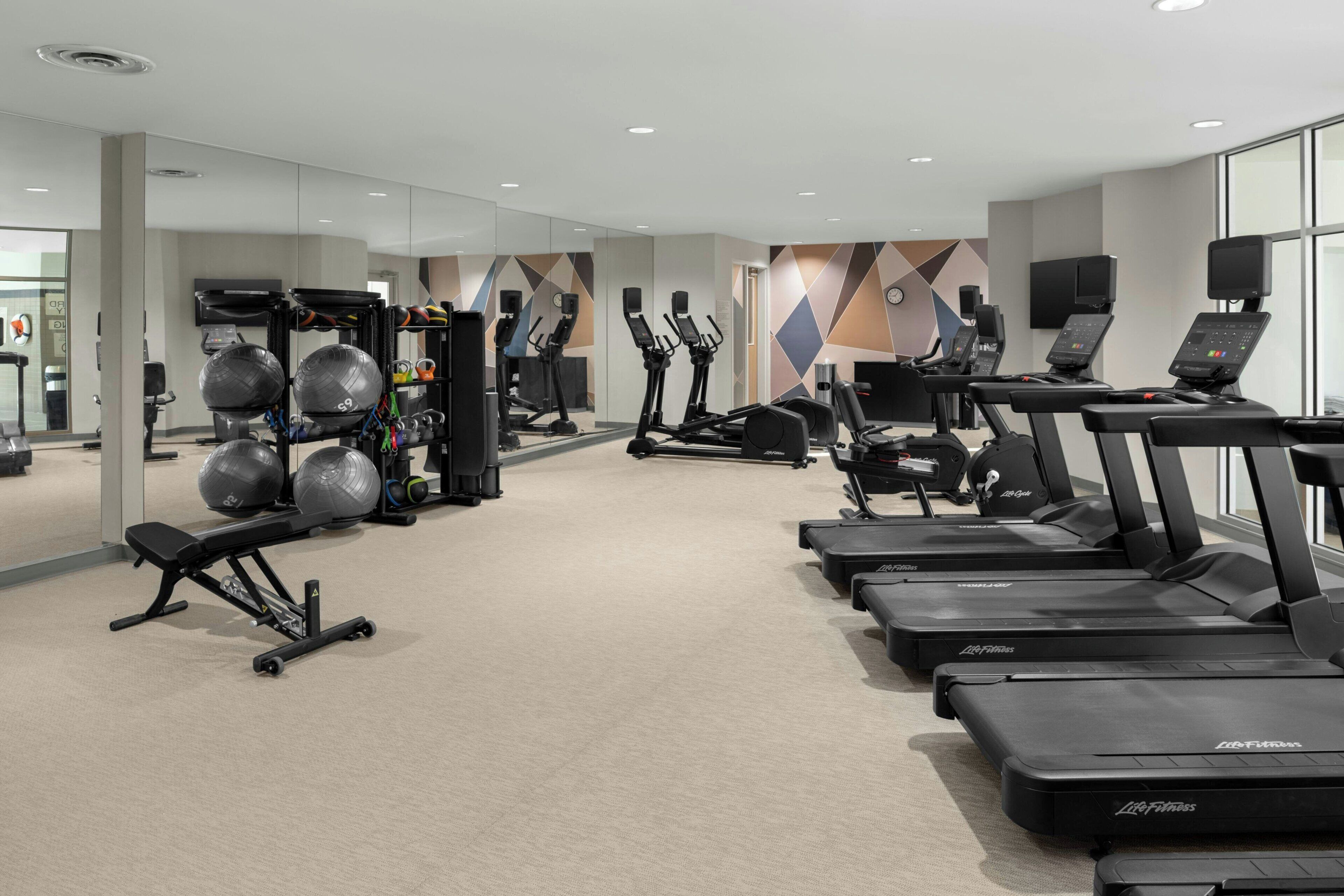 Ein modernes Fitnessstudio mit Laufbändern, Kraftgeräten und Gymbällen.