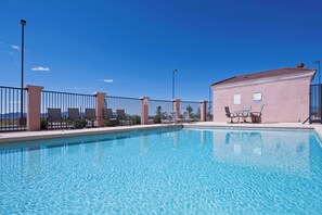 A clear blue pool with lounge chairs and a small building with a sign. - Holiday Inn Express & Suites Willcox by IHG (Willcox)