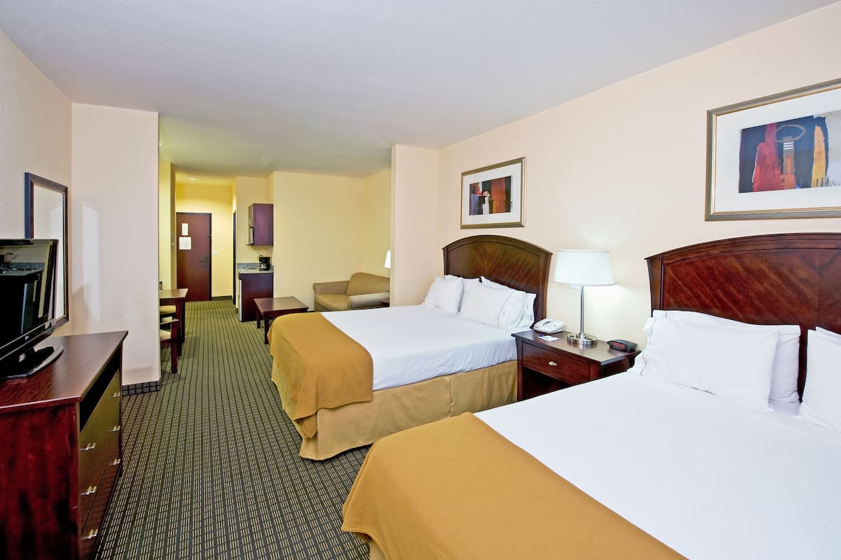 A hotel room with two beds, a desk with a computer, a chair, and a TV.