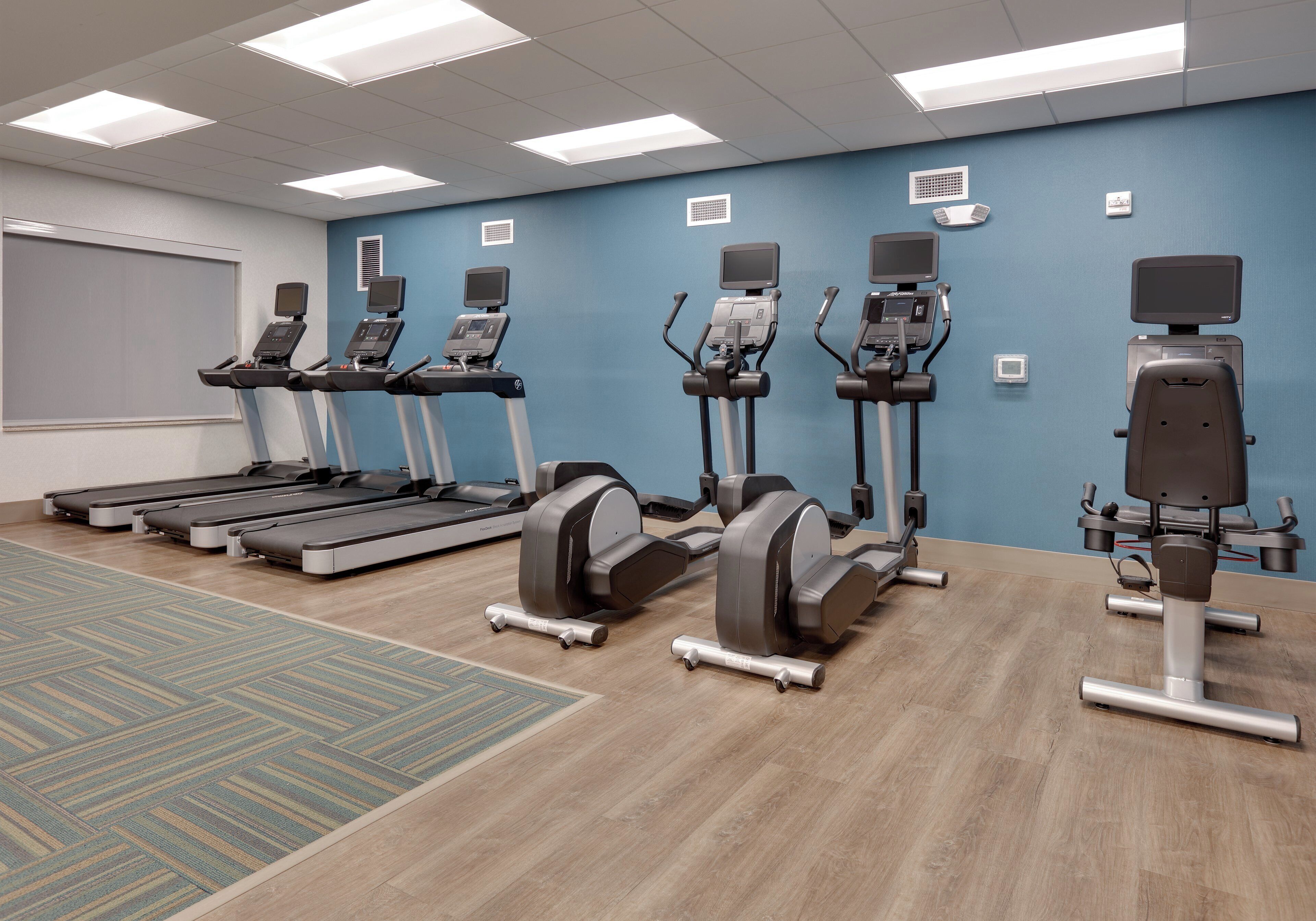A fitness room with treadmills, elliptical machines, and a stationary bike.