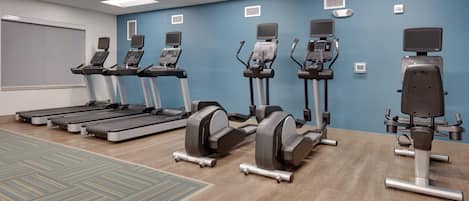 A fitness room with treadmills, elliptical machines, and a stationary bike.