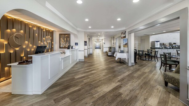 A hotel lobby with a reception desk, a long corridor, and a dining area.