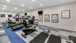 A gym with treadmills, stationary bikes, and exercise balls.