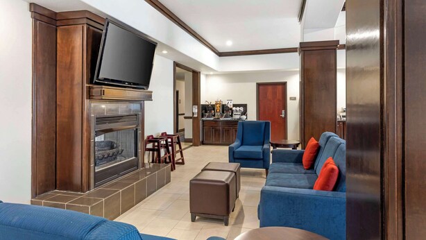 A modern living room with a fireplace, a flat-screen TV, blue sofas, and a bar area in the background.