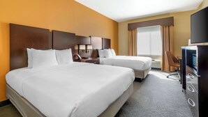 A hotel room with two beds, a desk, a chair, a television, and a large window with curtains.