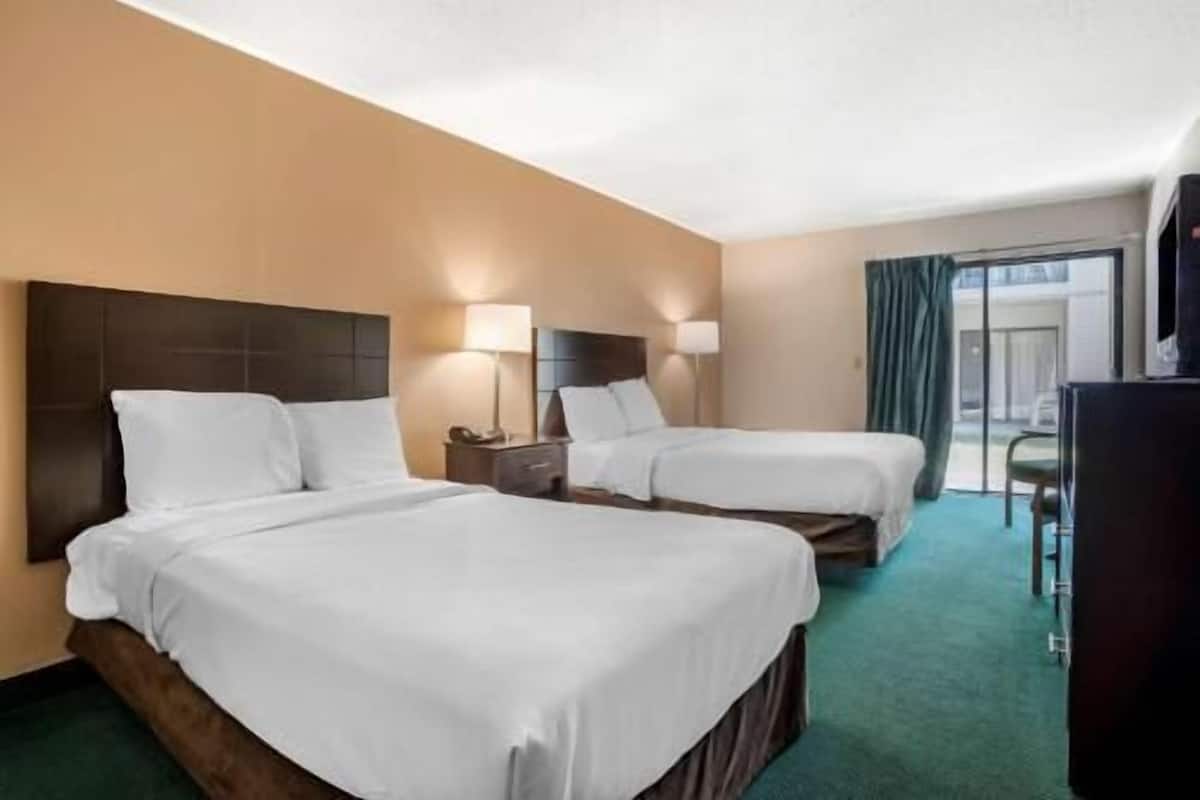 A hotel room with two beds, a desk, and a chair.