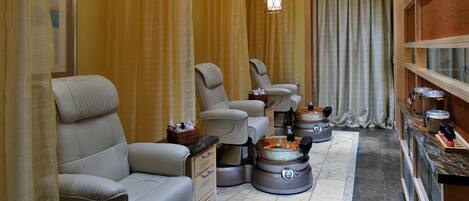 Un cuarto de spa con varias sillas de masaje, una tina de hidromasaje para pies y un área de recepción con mostrador y espacio de almacenamiento.
