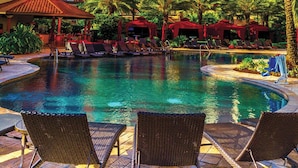 A hotel with a large pool area, palm trees, and lounge chairs. - L'Auberge Casino Resort Lake Charles (Lake Charles)