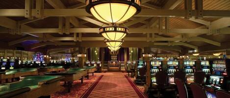 Un casino con máquinas tragamonedas, una mesa de billar y un pasillo alfombrado.