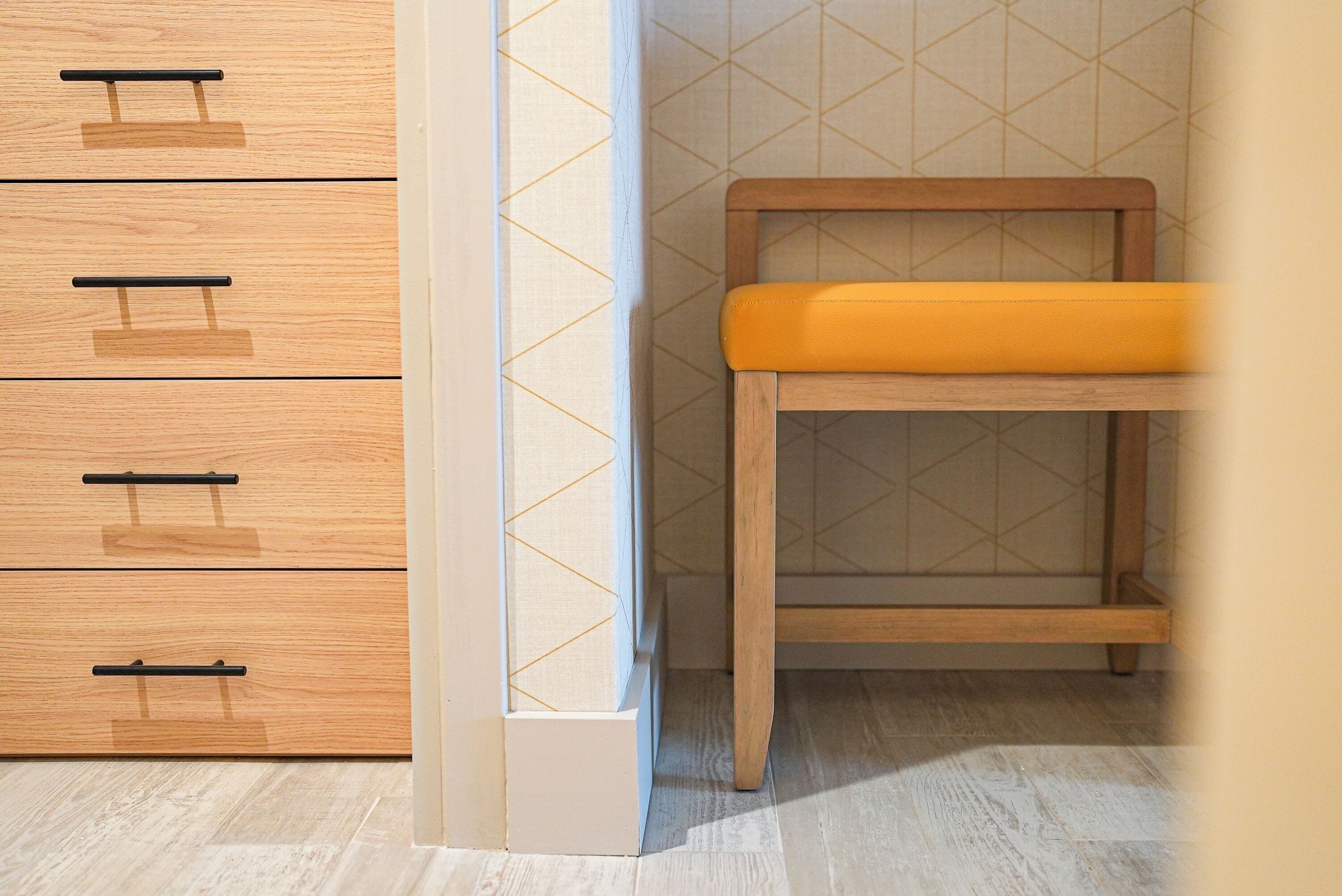 A wooden cabinet with drawers and a bench with a cushion.