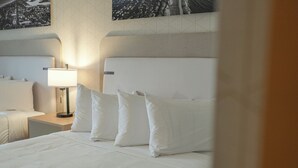 Habitación de hotel con una cama grande, una mesita de noche con lámpara y una vista de la ciudad en la pared.