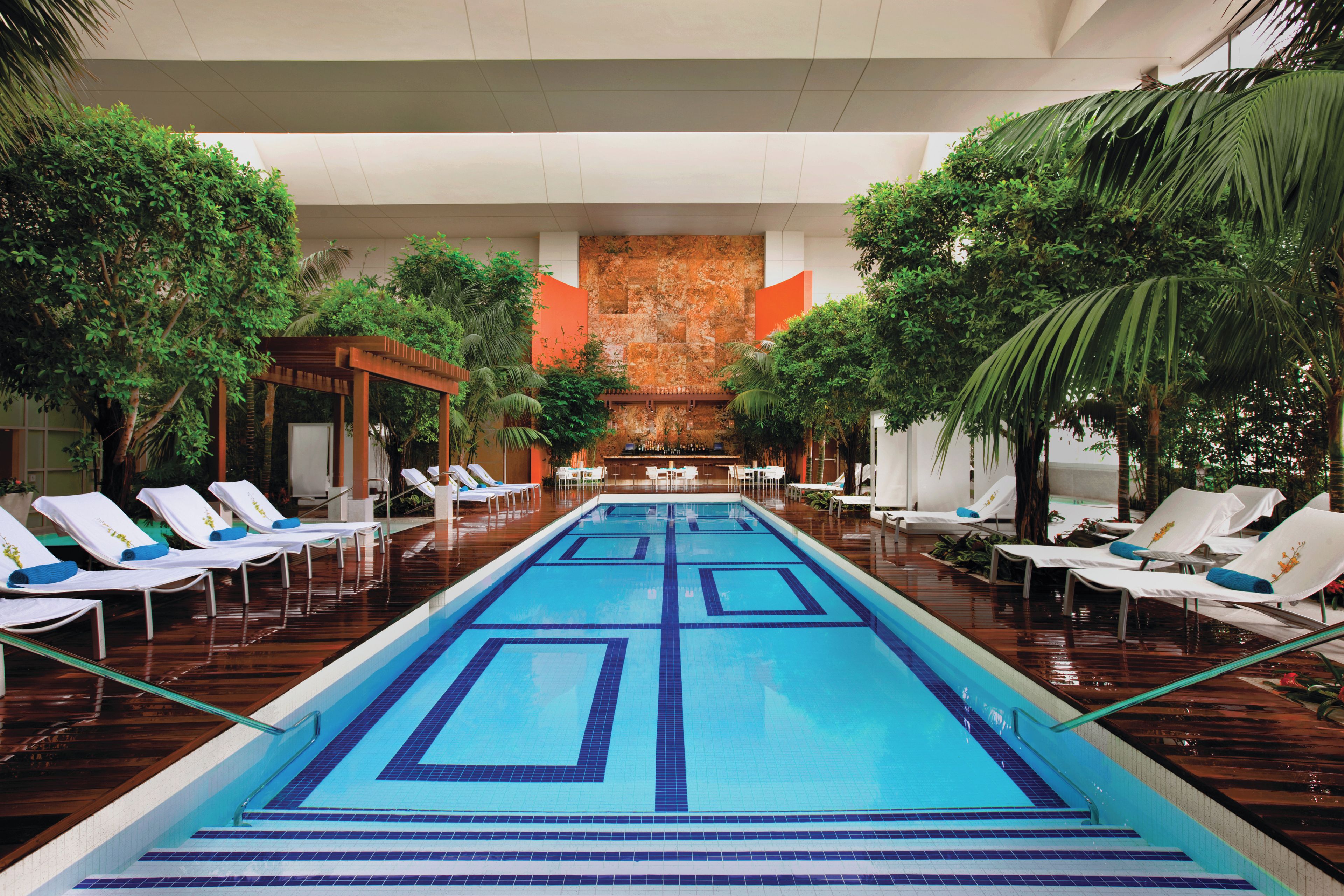 A swimming pool with lounge chairs and a bar area, surrounded by greenery.