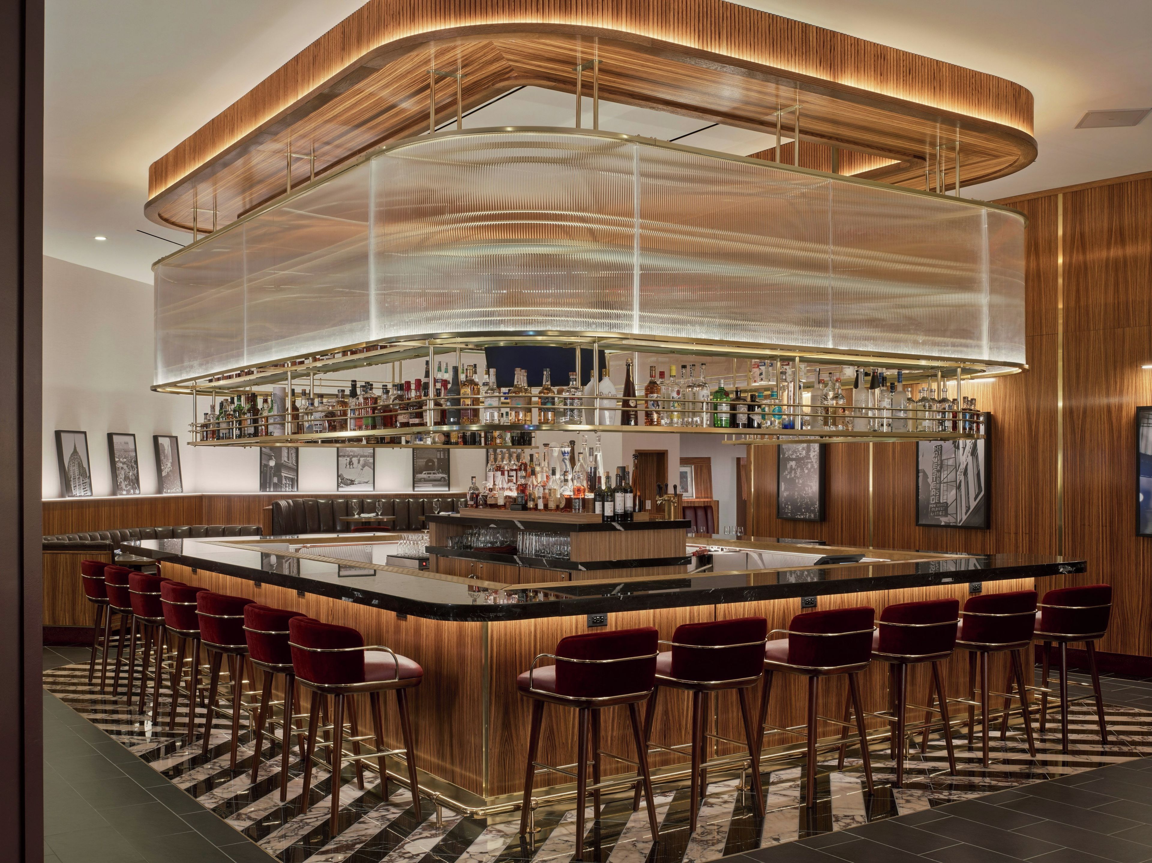 A bar area with a curved ceiling, multiple shelves of bottles, and red bar stools.