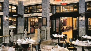 A spacious indoor dining area with multiple tables and chairs, a visible restaurant named "Metropolitan," and a brick column structure. - MGM Tower at Borgata (Atlantic City)