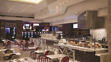 Um restaurante moderno com piso de mármore, cadeiras vermelhas e diversos alimentos expostos em uma vitrine de vidro.
