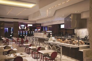 A modern restaurant with marble flooring, red chairs, and a variety of food displayed in a glass case. - MGM Tower at Borgata (Atlantic City)