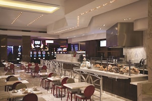 A modern restaurant with marble flooring, red chairs, and a variety of food displayed in a glass case.