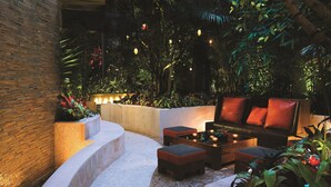 An outdoor seating area with a curved bench, a sofa, and a coffee table, surrounded by lush greenery and decorative lighting. - MGM Tower at Borgata (Atlantic City)