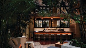 A bar area with a long counter and multiple stools, surrounded by indoor plants and a cozy seating area with cushions. - MGM Tower at Borgata (Atlantic City)
