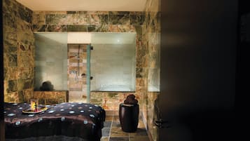 A bathroom with a shower, a bed with a polka dot bedspread, and a decorative vase.