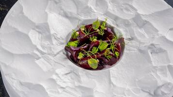 A white plate with a beet salad on a textured white surface.
