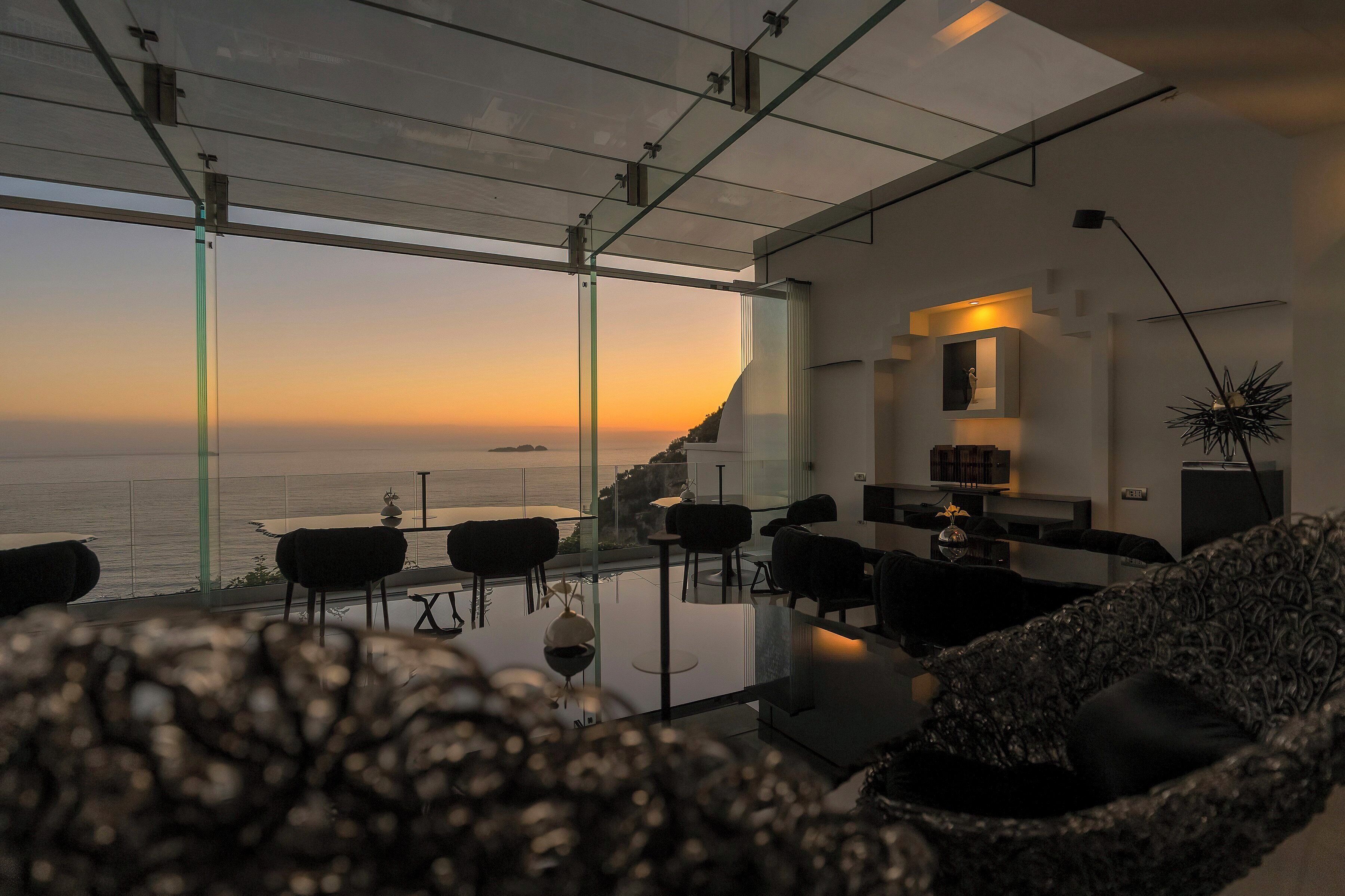 Un salon moderne avec vue sur l’océan, de grandes fenêtres et un mobilier contemporain.