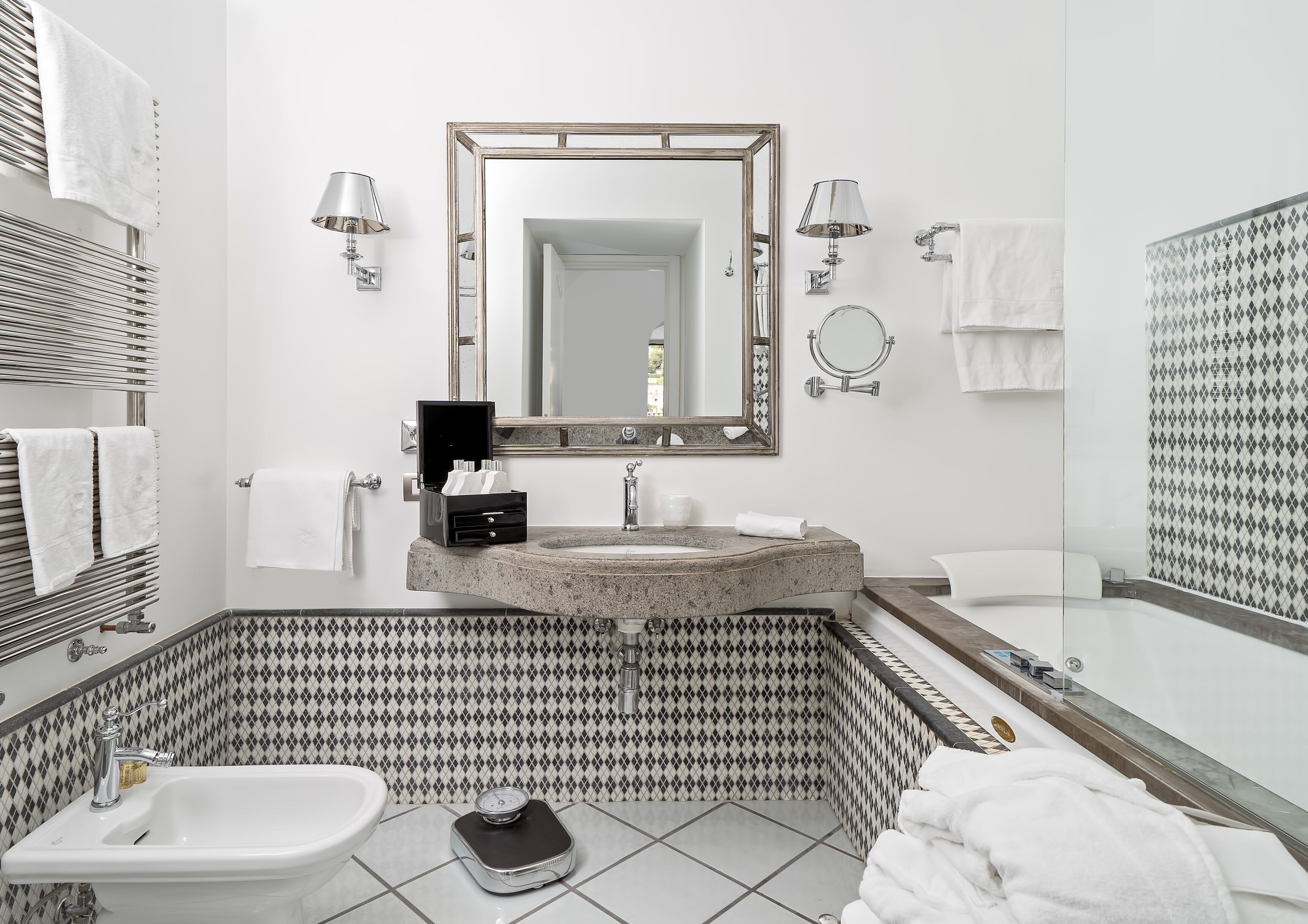 A modern bathroom with a freestanding bathtub, a large mirror, a sink with a marble countertop, and a toilet.