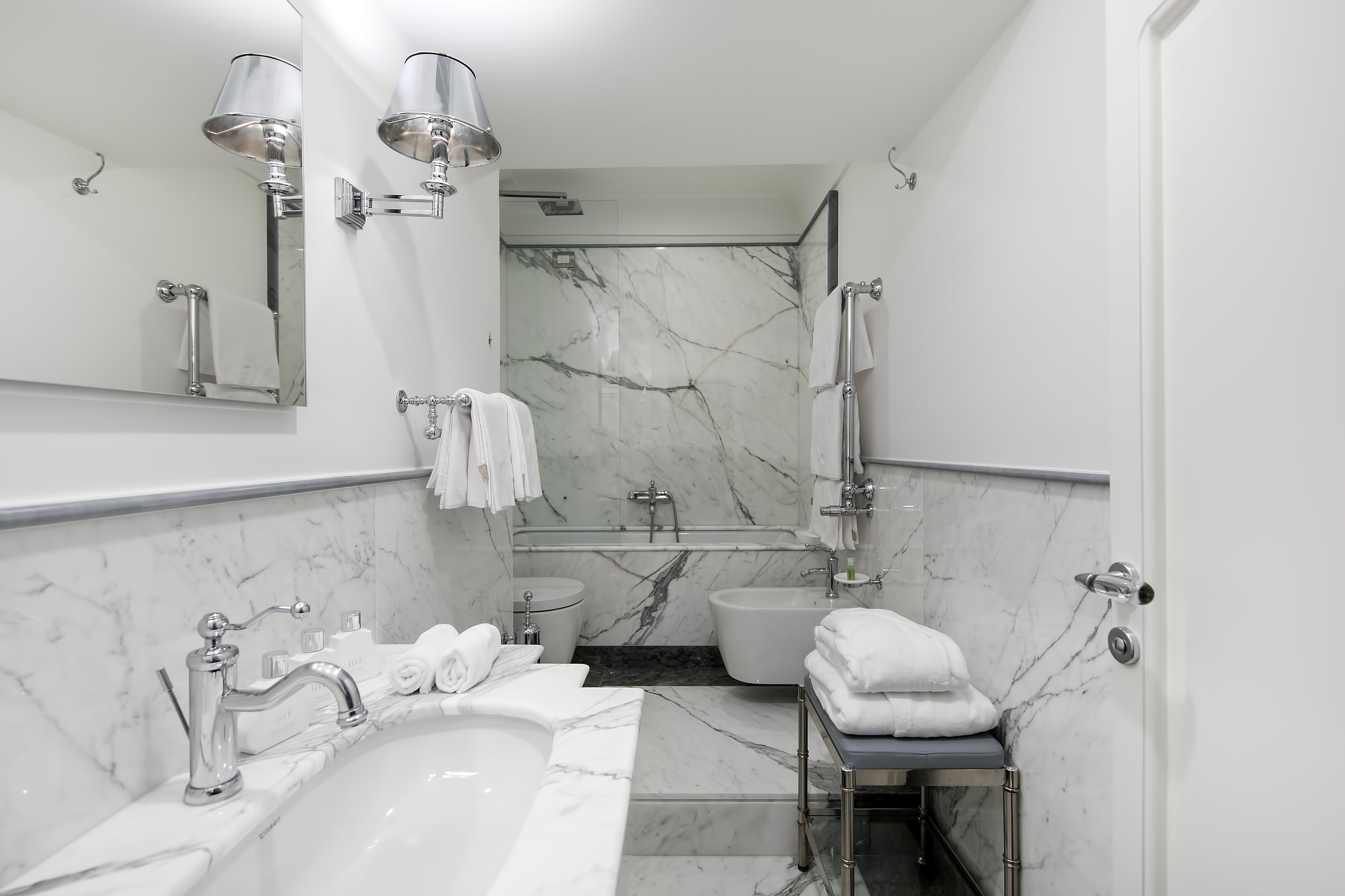 A modern bathroom with a marble sink, a bathtub, and a shower area.