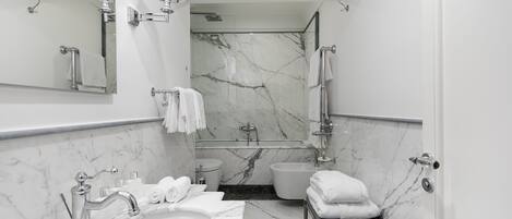 A modern bathroom with a marble sink, a bathtub, and a shower area.