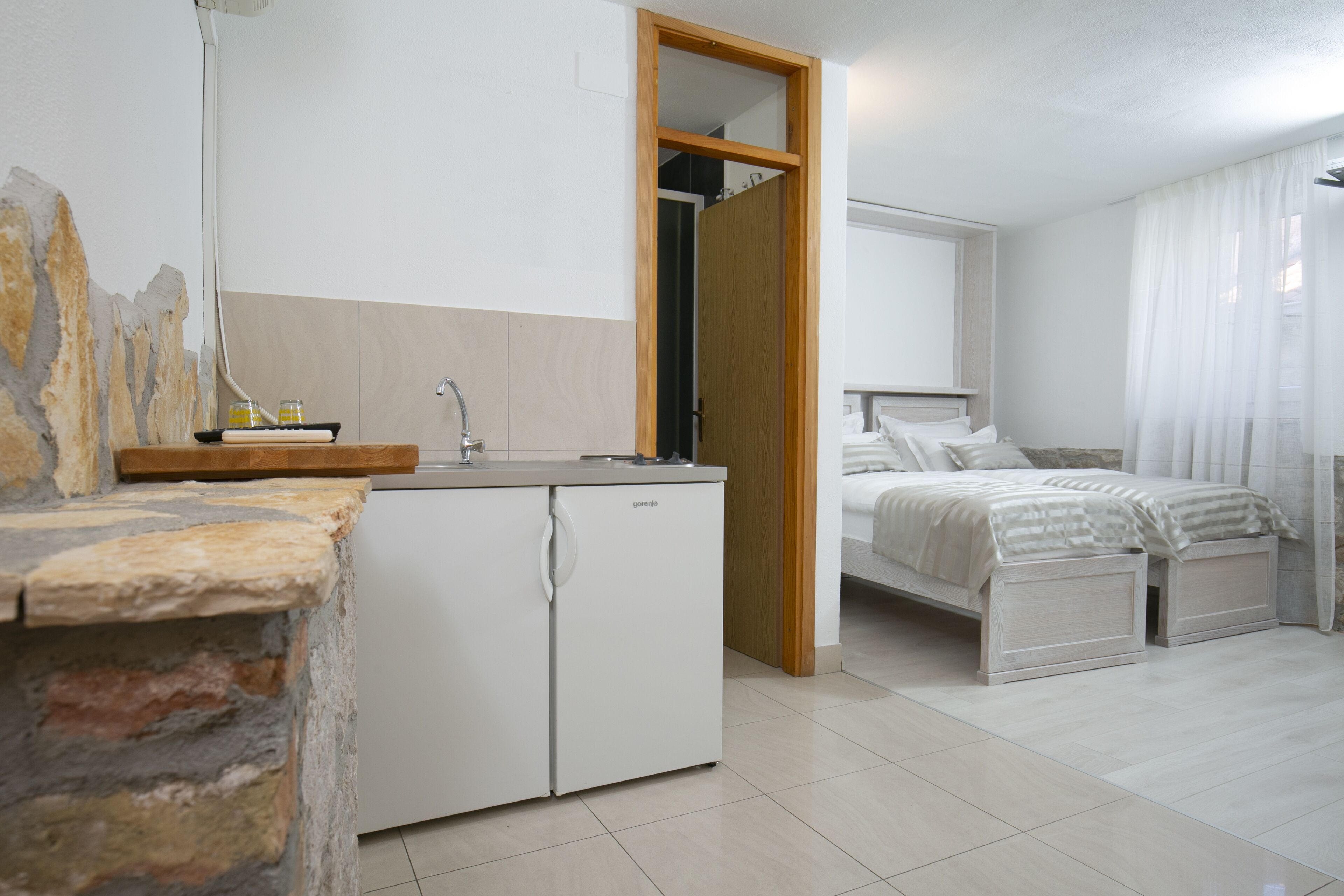 A compact hotel room with a kitchenette, a bed, and a bathroom.