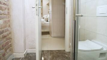 A bathroom with a glass shower enclosure, a toilet, and a sink.