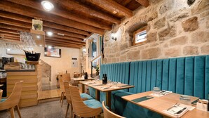 A restaurant with wooden tables, teal cushioned booths, stone walls, and a wooden ceiling. - Villa Matejuska Heritage (Split)